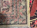 an antique persian rug with a red and black border and fringes