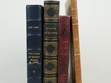 several old books are stacked on top of each other on a white surface