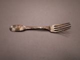a close up of a fork on a table with a gray background
