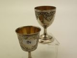 deux gobelets en argent posés sur une table blanche