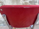 a red chair sitting in front of a stone wall
