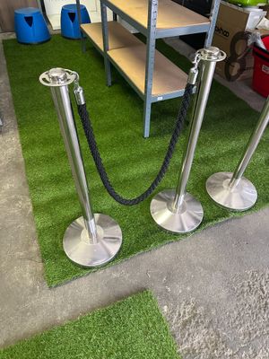 three metal poles that are on the grass near a shelf