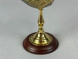 a golden clock on a wooden stand on a table