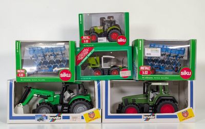 three green tractors in boxes on a white surface
