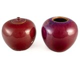 deux vases rouges posés l'un à côté de l'autre sur une surface blanche