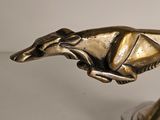 a bronze statue of a dog running on a pedestal