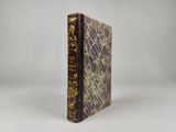 un livre marron orné d'une inscription dorée, posé sur une surface blanche