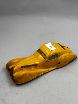 petite voiture jaune en plastique posée sur une surface blanche, avec une étiquette sur le côté