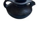 un petit pot noir muni d'une anse, sur fond blanc