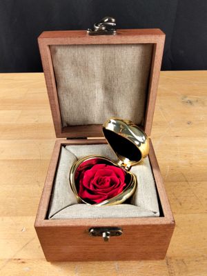 une petite boîte en bois contenant une rose rouge