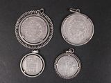 three silver coin pendants on a black surface with a black background