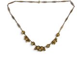 un collier en or orné de fleurs sur une chaîne, sur fond blanc