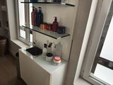 a shelf with bottles and soaps on it next to a window