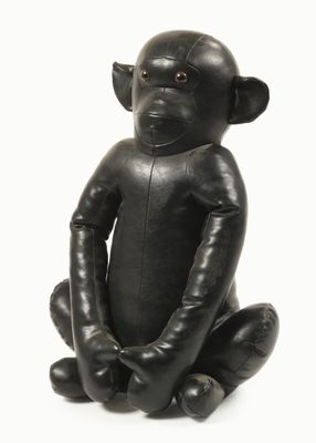 un singe noir assis par terre, les jambes croisées