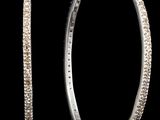 un gros plan sur une paire de boucles d'oreilles créoles sur fond noir