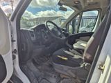 l'intérieur d'une camionnette blanche dont la porte est ouverte et le siège conducteur rabattu