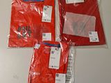Trois t-shirts rouges sont emballés dans des sacs en plastique sur une table