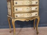 une petite commode posée sur un pied, adossée à un mur