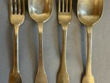four spoons and a fork are lined up on a table