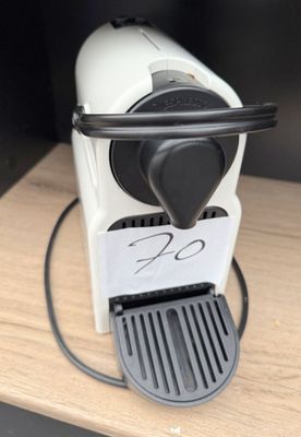 a white coffee machine with a black handle on a table