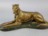 statue d'un chien doré couché sur un socle vert