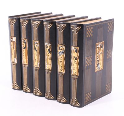 trois livres noirs aux tranches dorées sont alignés sur une surface blanche