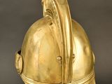 an antique gold helmet on a metal stand against a black background