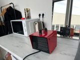 a red toaster sitting on a counter next to a white microwave