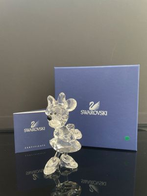 une figurine de Mickey Mouse en verre transparent posée à côté d'une boîte bleue