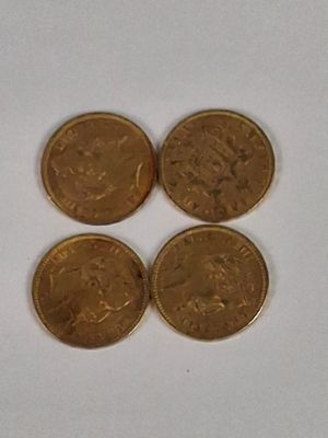 four gold coins sitting on top of each other on a white surface