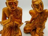 pair of gold statues of a man and a woman sitting on the ground