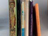 Plusieurs livres sont alignés sur une étagère à côté d'un vase