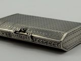 un étui à cigarettes ancien en argent posé sur une table, sur fond blanc