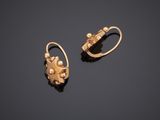 a pair of gold earrings with pearls on a black surface