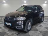 La BMW X5 est garée dans une grande pièce au sol à carreaux.