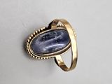 a close up of a gold ring with a blue stone in it