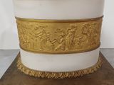 a white and gold vase on a stand with gold trimming