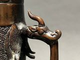 a bronze vase with a dragon handle on it
