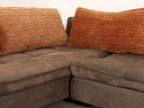 a brown couch with orange pillows on it in a living room