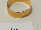 une bague en or et une étiquette posées sur une table blanche