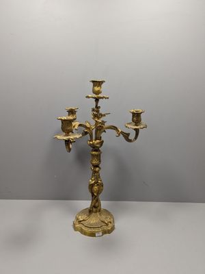 un candélabre en laiton à trois bougies, posé sur un socle
