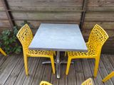 des chaises jaunes et une table sur une terrasse en bois, avec une plante