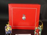 Deux figurines représentant des personnes en costume traditionnel chinois sont assises devant une boîte rouge.