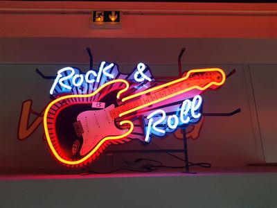 a neon sign that says rock and roll with a guitar on it