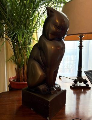 a statue of a cat sitting on a desk next to a lamp