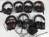 Plusieurs casques audio noirs sont alignés sur une table blanche