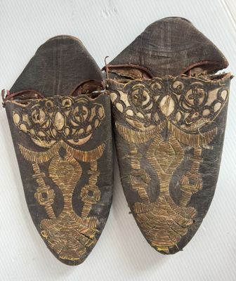 deux paires de chaussures ornées de motifs dorés sur un fond blanc