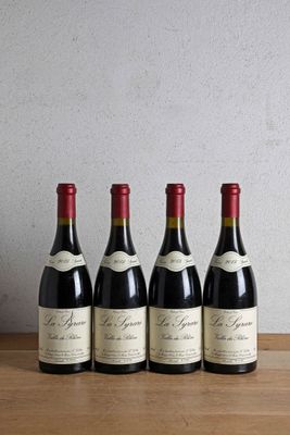 four bottles of wine are lined up on a wooden table