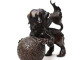 a statue of a dog with a ball on a white background