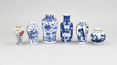 Plusieurs vases bleus et blancs sont alignés sur une surface blanche